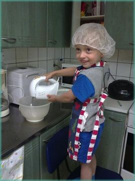Pikku leipuri vatkaa taikinaa keittiössä.